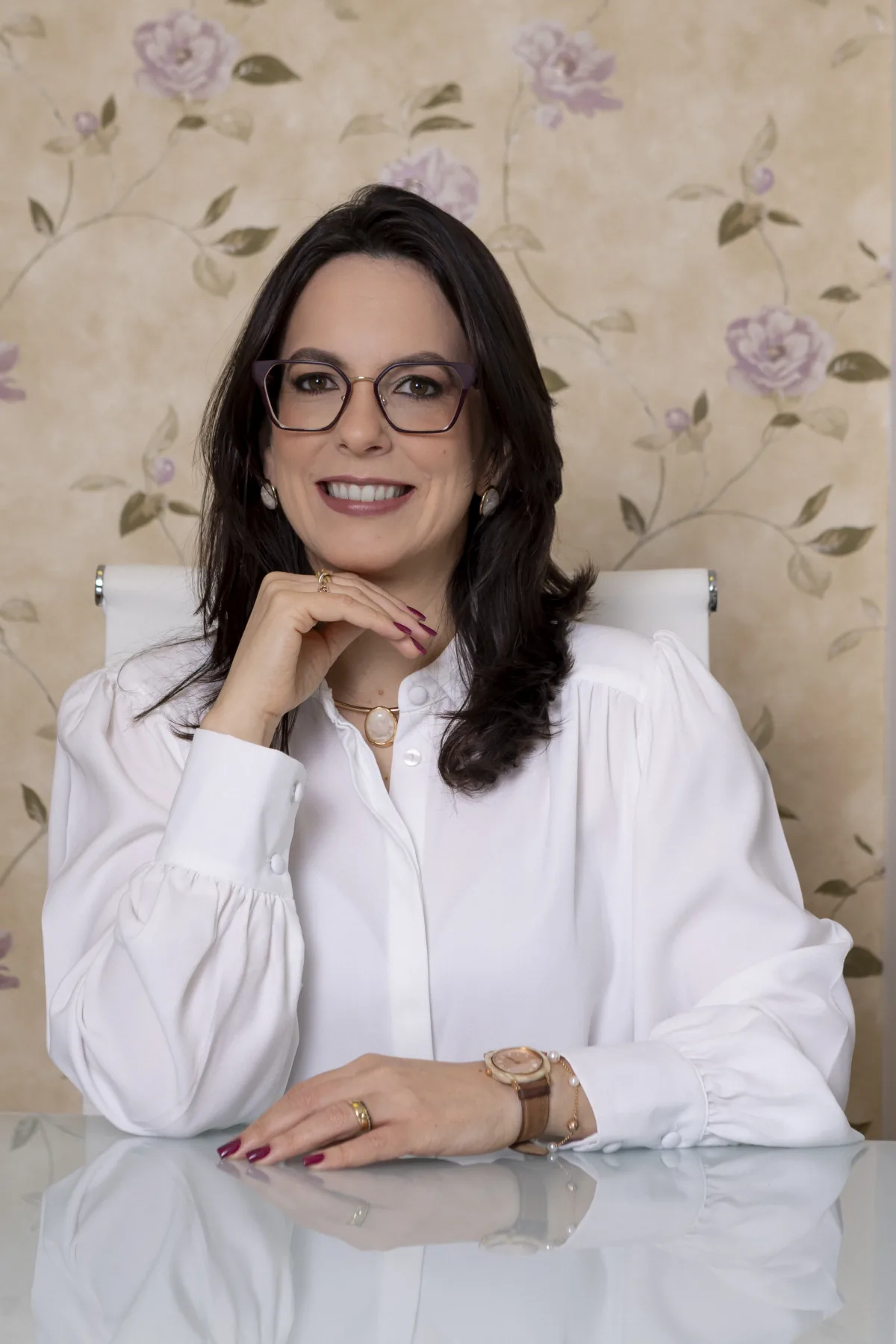 Dra. Thaisa Motta sorrindo, sentada à mesa.