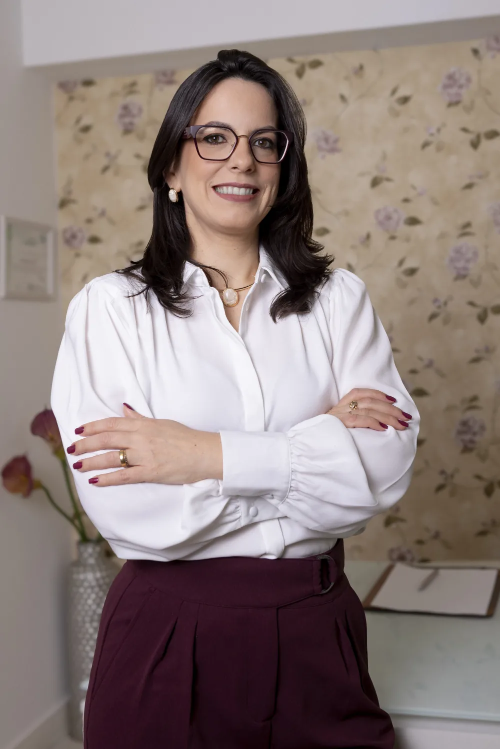 Retrato da Dra. Thaisa Motta sorrindo, de braços cruzados.
