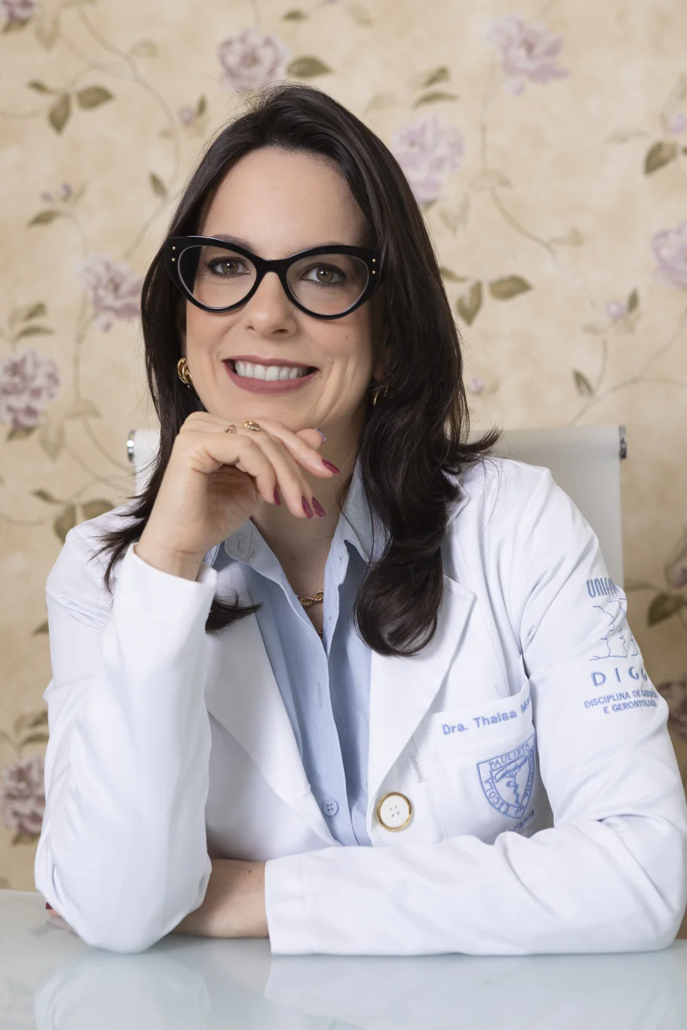 Dra. Thaisa Motta sorrindo, com jaleco que traz o bordado da UNIFESP.